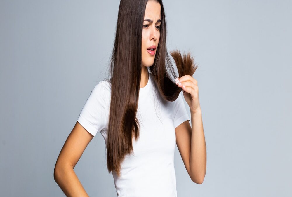 Jóven mujer con remera blanca preocupada por la caída estacional del pelo